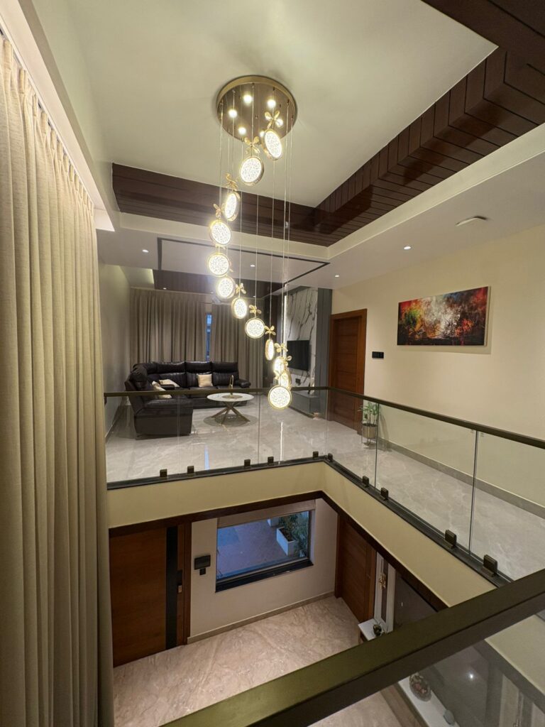 Luxury double-height living room interior with designer chandelier lighting, glass railings, and modern false ceiling by LEVENUS